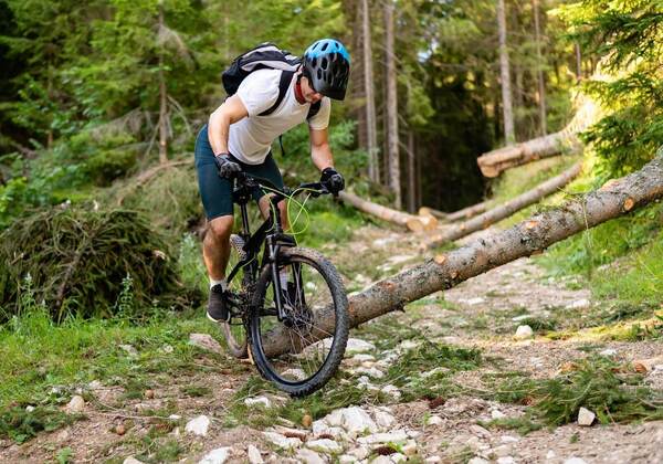 Persona adulta pedaleando con casco por un sendero arbolado