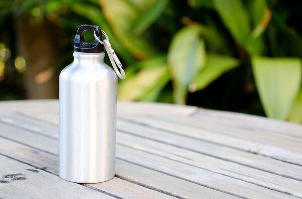 Botella reutilizable con agua sobre una mesa clara